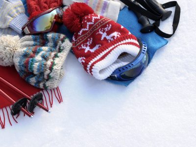 Winter sports background with ski poles, goggles, hats and gloves with copyspace (picture taken in fresh snow with directional winter sun).